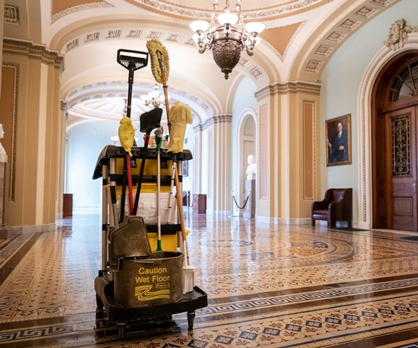 cleaning cart with mops and disinfectant in an empty hallway