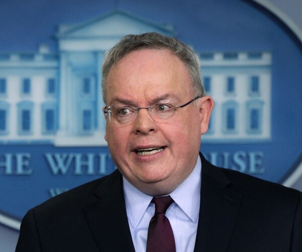 jim carroll stands in front of a white house logo and speaks