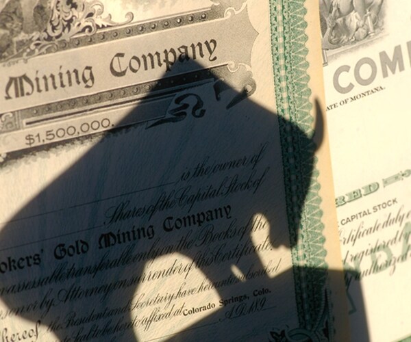 shadow of a bull over top of antiquated mining stock certificates 