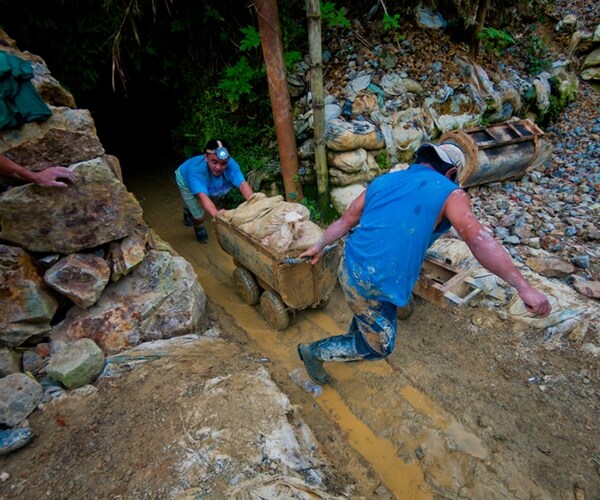 A group of private miners pulls out a make-shift cart full of sacks of gravels containing gold particles