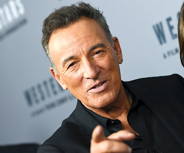 musician bruce springsteen stops for a photo on a red carpeter
