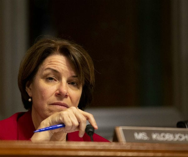 Sen. Amy Klobuchar, is shown holding a blue pen as she listens during a hearing on Capitol Hill.