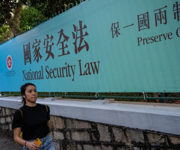 woman walking past sign reading national security law