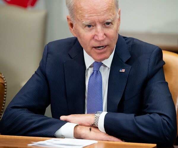 joe biden sits with arms folded on table