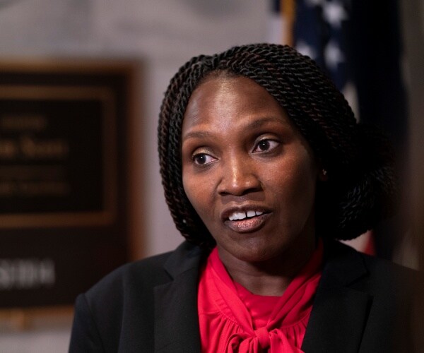 cooper-jones in a red top and black jacket speaking