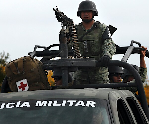 the mexican military soldier rides on the back of a military vehicle behind a high-powered weapon