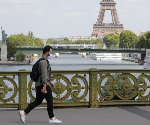 man wearing mask walks near eiffel tower