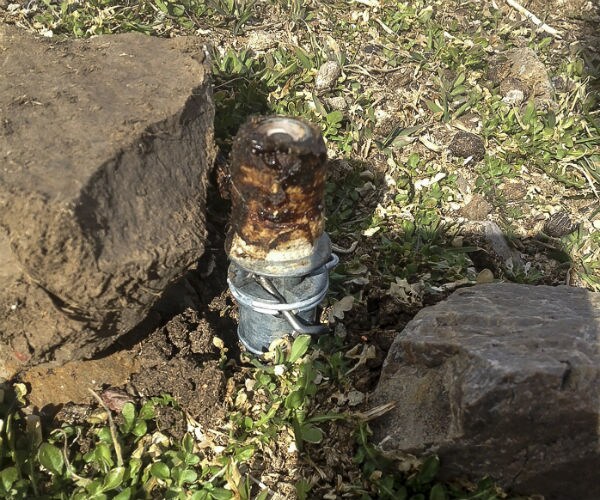 A M-44 trap is shown between two large rocks. M-44 is also known as “cyanide bombs"