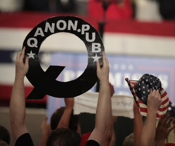 man holds up a qanon sign