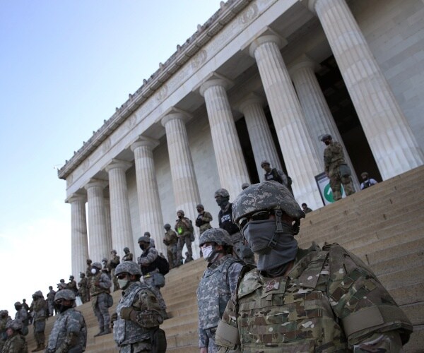 national guard in camouflage uniforms stand in front of the lincoln memorial