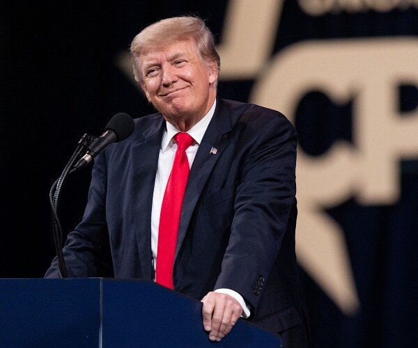 donald trump smiles as he leans on podium