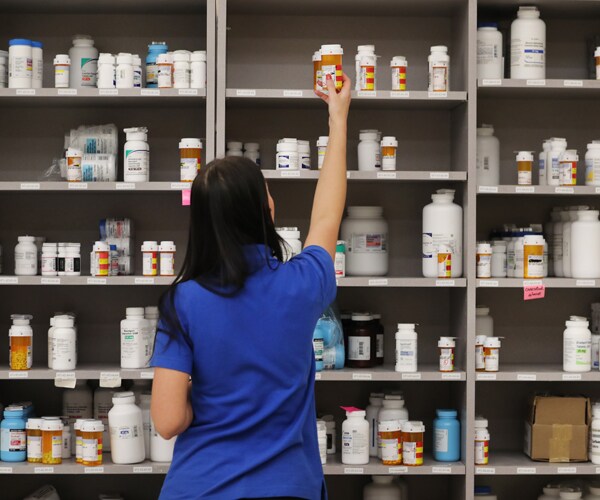 a pharmacy technician reaches for medicine