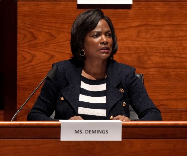 demings in a black coat and white and black striped top 