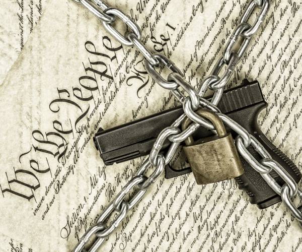 a copy of the preamble to the constitution with a handgun locked in chains on top of it