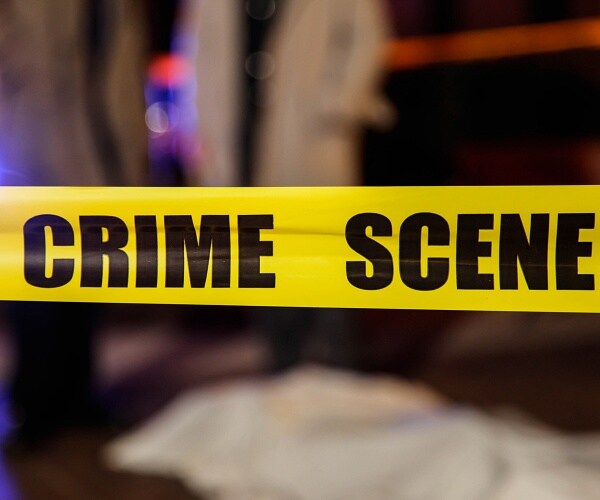 crime scene tape with blurred covered body and two people in background