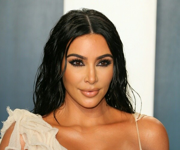 kardashian in a cream colored dress and black eyeshadow