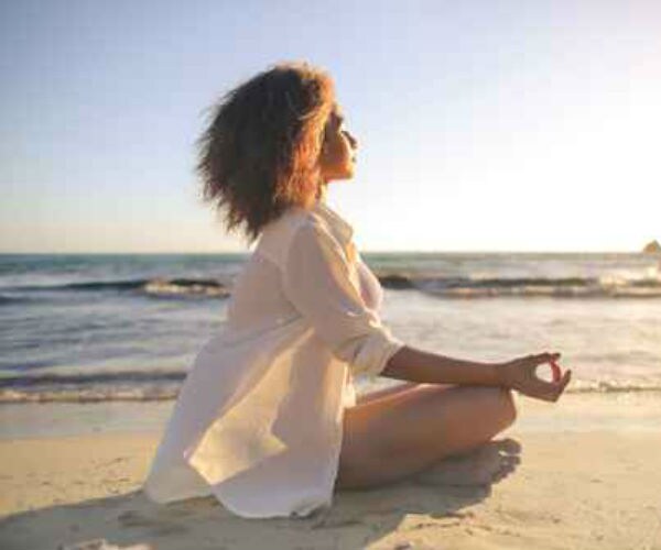 woman doing meditation on beach