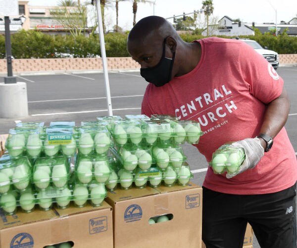 a man is shown stacking eggs for distribution in a church parking lot in vegas.