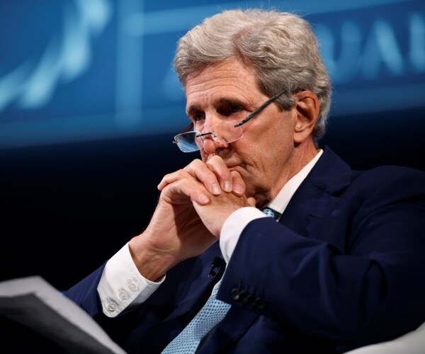 John Kerry sits in a chair with a book on his lap