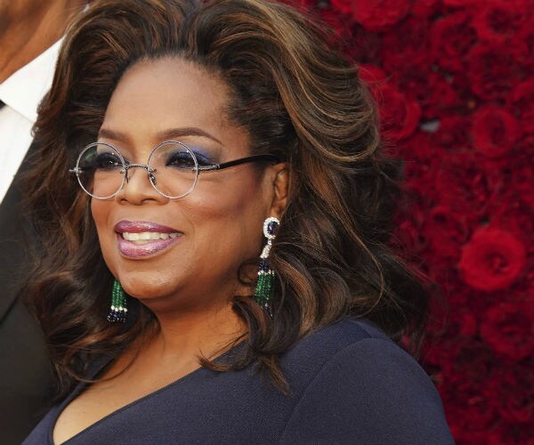 oprah winfrey is seen in a blue dress, wearing glasses