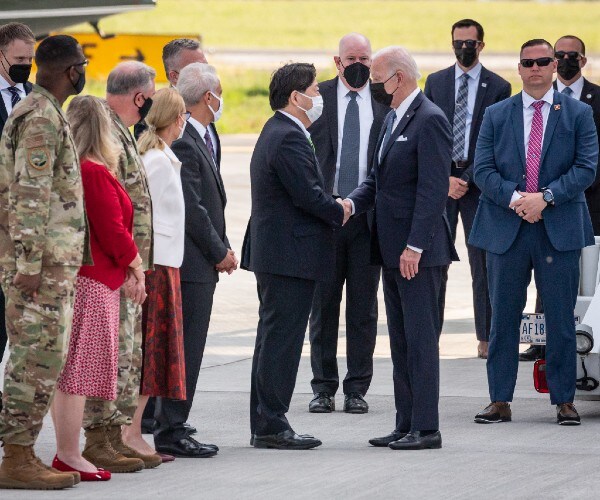 biden shaking hands with dignitaries on an airport tarmac