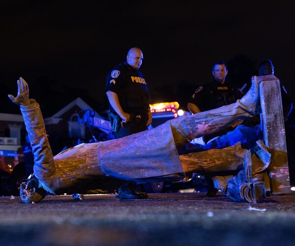 police officers look at a fallen jefferson davis statue