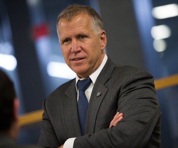 thom tillis has his arms crossed while speaking with someone in the halls of congress