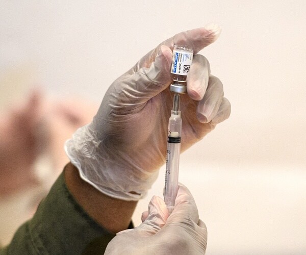 healthcare worker prepares needle with vaccine