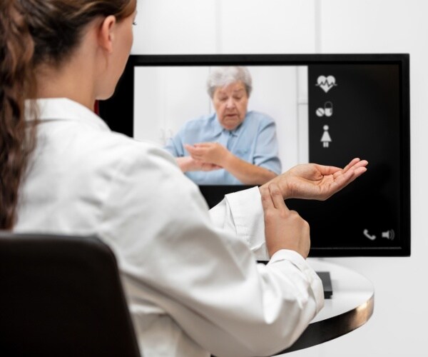 telemedicine appointment with a doctor helping a patient feel her pulse in a computer video