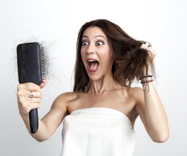 woman seeing her hair loss on brush in horror