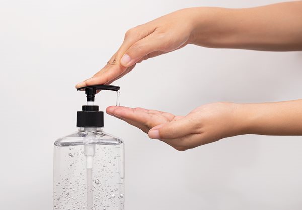 hands arms of person getting hand sanitizer from bottle with pump