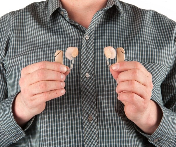 a man holds hearing aids in both hands