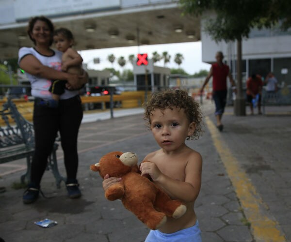 Sergio Jr., 18-months, plays with a teddy bear as he stands with other migrants awaiting to request asylum in the U.S.