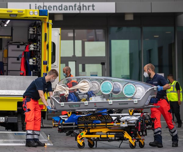 German army emergency personnel load portable isolation unit into their ambulance