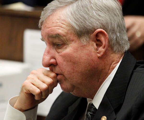 cooley in a suit resting his hand on his head