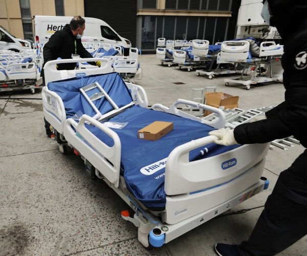 workers pushing hospital beds outside mount sinai hospital and preparing them for patients