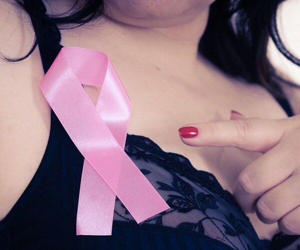 woman pointing to pink ribbon on her bra