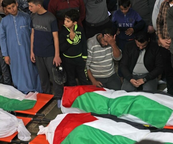 mourners over palestinian-flag draped bodies