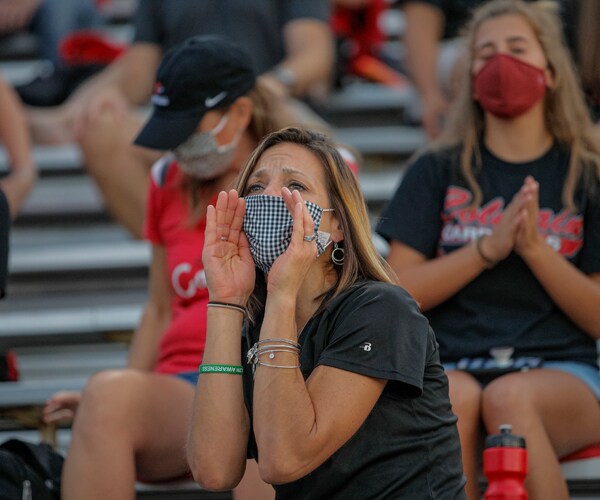 a fan wearing a face mask yells at a football game