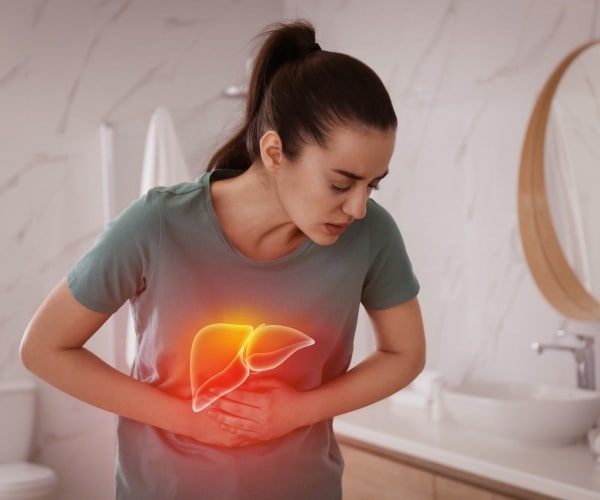 woman in bathroom holding stomach with liver highlighted in red