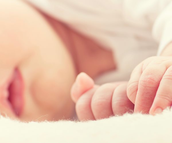 close-up image of a baby's hands and head