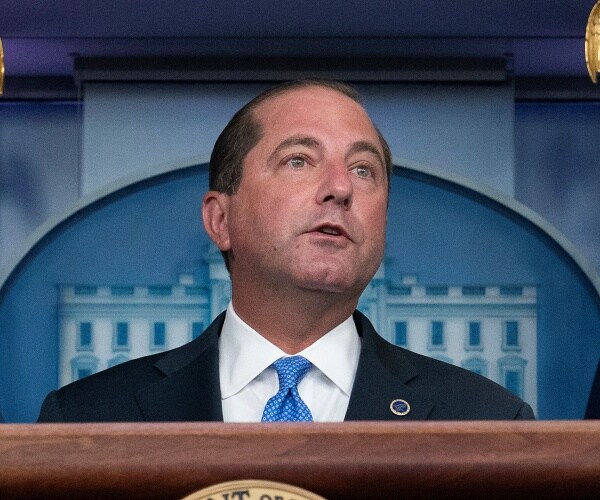 alex azar stands behind podium