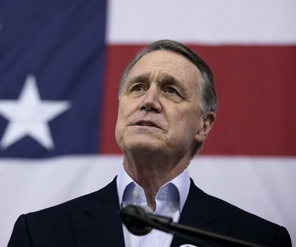 david perdue stands in front of american flag