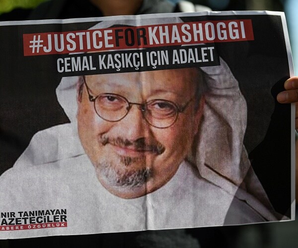 man holds newspaper showing justice for khashoggi ad 