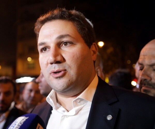 gemayel in a suit and white shirt being interviewed outside