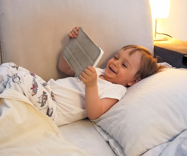 a toddler looking at a tablet and laughing