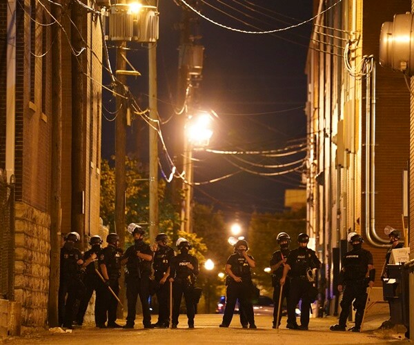 louisville police block off an alley at night, as they wear helmets and hold sticks