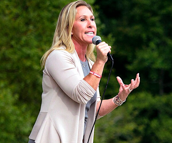 marjorie taylor greene speaks into a mic at an outdoor rally
