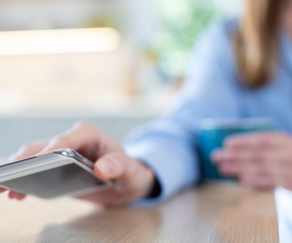 woman drinking coffee, putting her phone down upside down 
