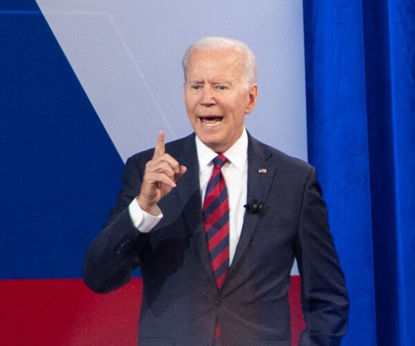 joe biden holds up hand while standing onstage